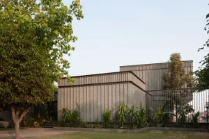 A modern architectural structure with a concrete exterior surrounded by greenery.