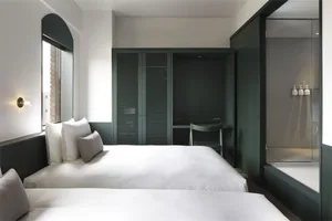A modern bedroom featuring two beds with white bedding and a minimalist design.