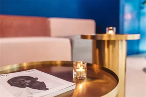 A modern coffee shop featuring metallic furniture with a lit candle and a magazine on a table.