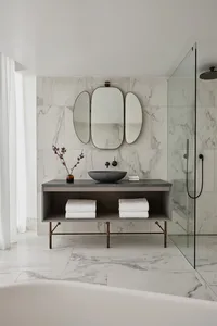 A modern bathroom with marble tile walls and floor, featuring a floating vanity, a black stone sink, and a walk-in shower wit