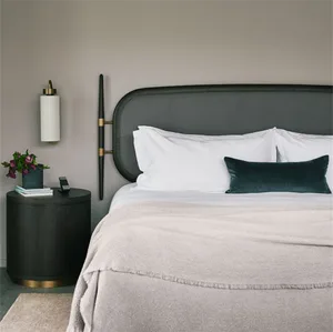 A minimalist bedroom with a dark wood headboard and light bedding.