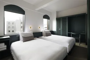 A minimalist bedroom with white textured surfaces and a white bed.