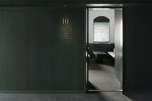 Modern office space with dark green walls, a metal door, and white blinds.