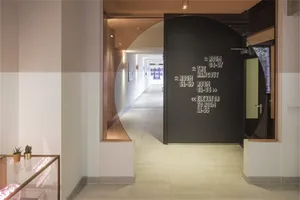 A modern office hallway featuring a black glass door with text.