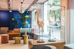 Two flamingo sculptures in glass cases within a modern retail storefront with glass walls and light fixtures.