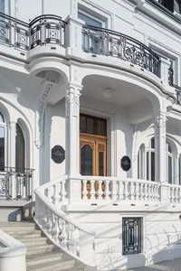 An impressive entrance with white marble staircase and elegant black ironwork.