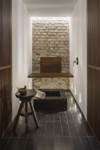 A minimalist bathroom featuring a stone basin surrounded by wooden panels and tiles.