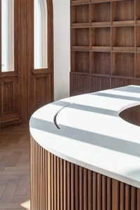 A modern, white countertop with a curved edge and wooden slat base.