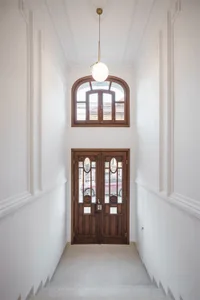 Modern entrance hall with wooden double doors and a matching semicircular transom window.