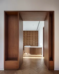 A modern office space featuring wooden walls, flooring, and a reception desk.