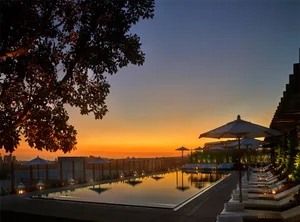 Sunset view of a luxury hotel poolside with metallic reflections and modern architecture.