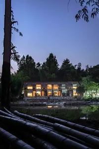 A waterfront house with illuminated windows by a lake at dusk.