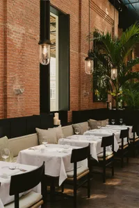 A restaurant interior with brick walls and pendant lights.