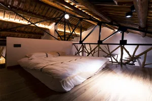 A modern bedroom designed with white lighting, featuring a bed with minimalist bedding and an exposed wooden ceiling with met