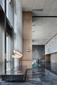 Modern hotel lobby with marble, concrete, and wooden elements.