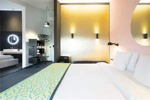 Modern hotel room with a bed, bathroom, and minimalistic design.