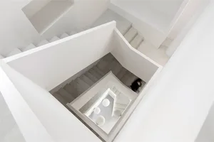 A modern interior with concrete flooring, viewed from above with a person walking on a different level.