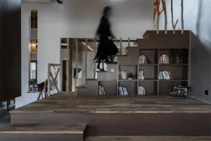 A modern office library with wooden flooring, concrete walls, and metallic shelving units.