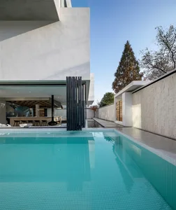 Modern outdoor pool area with a minimalist design and concrete walls and flooring.