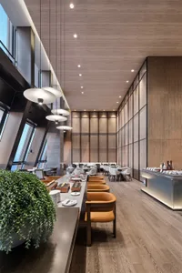 A modern restaurant interior with wooden furniture, pendant lights, and a large buffet counter.