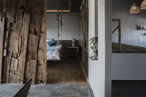 A rustic bedroom featuring wood walls, concrete floor, and a hanging wooden bed frame.