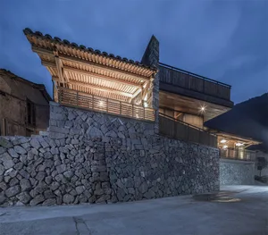 A contemporary residential exterior with stone and wood finishes at twilight.
