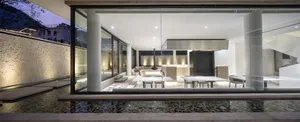 A modern residential interior featuring glass walls and metal elements.