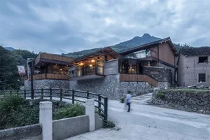 A modern residential house with stone, wood, and glass materials.