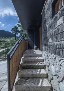 A stone staircase with a wooden railing leading up to a building exterior.