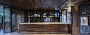 A warm wooden reception counter with integrated shelving and hanging lights.