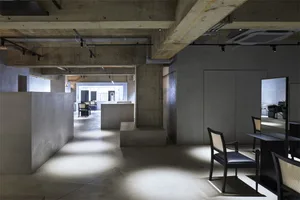 A spacious, industrial-style office interior with concrete walls, concrete cubes, and concrete countertops. The space feature