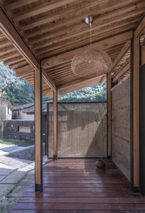 A minimalist residential exterior featuring a wooden porch with a woven light fixture.