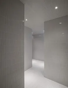 Interior view of a minimalist white tile bathroom with a clean, uncluttered design.