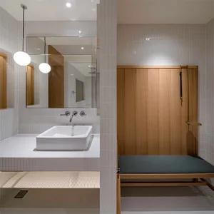 Modern minimalist bathroom with white tiled walls, white sink, and wooden paneling.