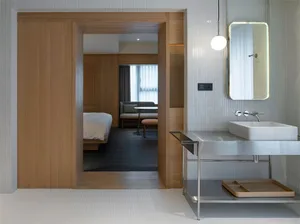 A modern bathroom with a floating vanity, white porcelain tiles, and a minimalist design.