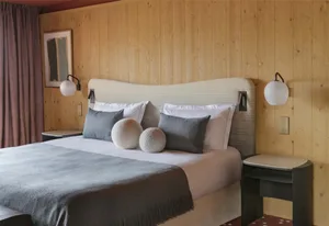 Modern bedroom with a gray bed and wooden walls.