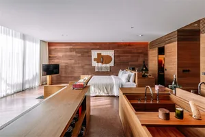 A modern bedroom with a wooden wall, white bedding, and a minimalist design.