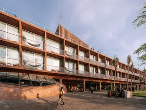 A modern building with wooden exteriors features large windows and balconies.
