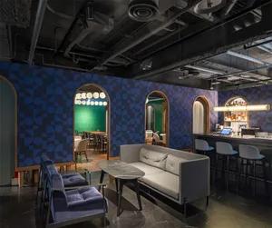 A modern cafe bar featuring a geometric patterned tile wall, painted accents, upholstered furniture, and a wooden floor.