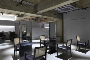 A modern hair salon with concrete walls and steel furniture.