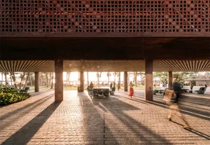 People walking under a modern public space with brick and concrete pavement and columns.