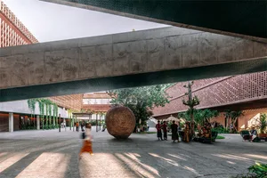 A modern, public space with a large concrete ball as a centerpiece.