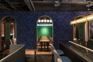 A modern restaurant interior with geometric patterns on the walls and a long dining table.