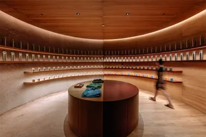 A modern retail shop with a wooden round counter and shelves filled with bottles.