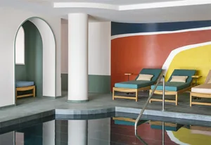 A modern spa interior featuring concrete flooring, colorful walls, and teal lounge chairs.