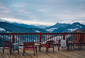 Veranda with wooden furniture overlooking snowy mountains
