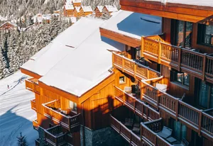 Multi-story ski resort buildings covered in snow with wooden balconies and windows