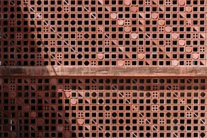 A wall featuring a design pattern made of red bricks with various geometric shapes and sizes.