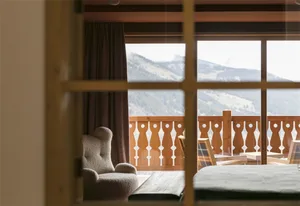 A cozy wooden room with a view of the mountains and a comfortable seating area.