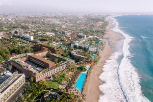 Aerial view of a beachside resort with a large pool area and multiple buildings.